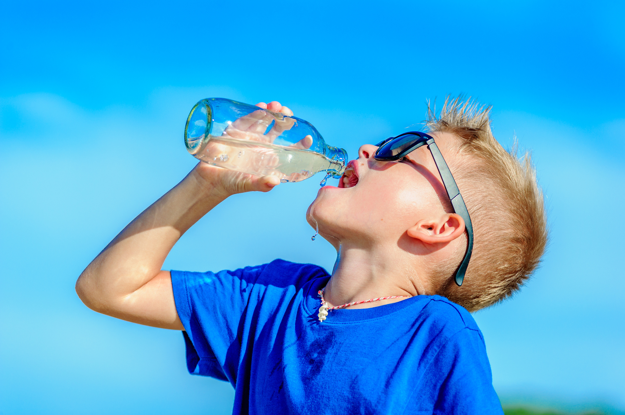 Portrait of a thirsty handsome boy in sunglasses drinking water on the Portrait of a thirsty handsome boy in sunglasses drinking water on the